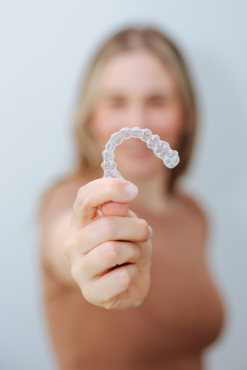 Woman happily showing off her Invisalign clear aligners